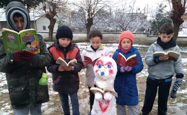 Kardan adam yapıp başında kitap okudular